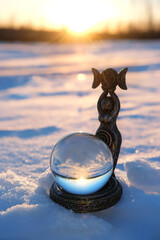 Magic crystal ball with goddess figurine on snow close up, winter nature background. wiccan altar for festive winter season. spiritual crystal practice. witchcraft ritual for winter solstice, Yule