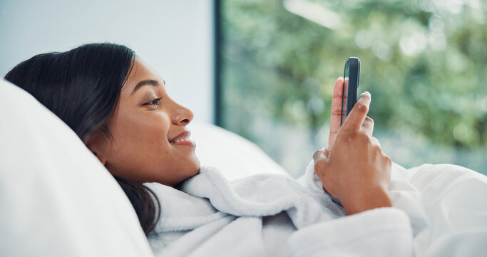 Mobile, relax and happy woman in bedroom for internet communication, online dating app or chat. Rest, bed or Indian girl with phone for social media post, morning notification or profile info in home - Powered by Adobe