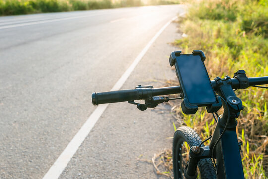 Bicycle parked on a rural roadside with smartphone mounted for navigation, symbolizing outdoor activity, travel route planning and freedom of exploration