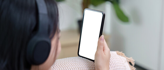 Digital Lifestyle. Young woman enjoying music on smartphone with headphones at home.