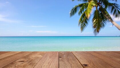 Fototapeta premium Wooden table top overlooking sparkling turquoise sea water with swaying coconut palm tree and clear blue sky background. Perfect tropical summer vacation banner concept