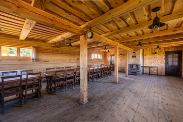 Fototapeta premium Spacious Rustic Wooden Event Hall Dining Area with Chairs and Tables Near a Cozy Fireplace