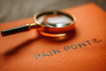 Magnifying glass and orange paper with text PAIN POINTS.