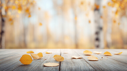Empty wooden table with autumn leaves, blurred forest bokeh background.