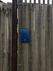 Blue mailbox on old wooden fence -Russian village life concept. Handmade phone photo, selective focus, no AI