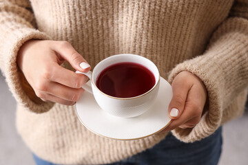 Young woman holding cup of tea at home, closeup