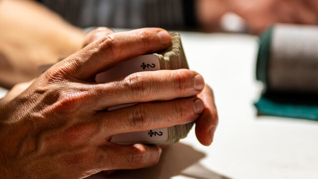 french tarot card game, close-up of a player’s hands holding the deck before dealing. symbolic scene of focus and anticipation during a friendly evening game in france, tradition and strategy