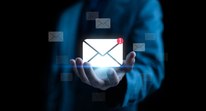 Businessman holding glowing email icon with new message notification, representing digital communication, marketing, networking, and online business connection.
