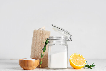 Jar of baking soda with lemon, cleaning sponge and twig on white grunge background