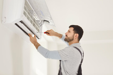 Service man installing, fixing repairing air conditioner unit, using screwdriver, focused...