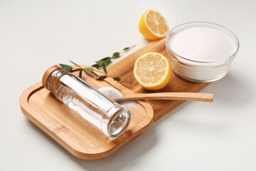Wooden boards with bowl of baking soda, vinegar and lemons on white background