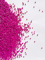 Rubine red masterbatch granules, polymer carrying rubine red pigment poured into a white background medium, suitable for product catalog design of plastic industry manufacturing company profiles