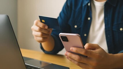 Man holding credit card and smartphone for secure online payment, e-commerce transaction, or mobile banking on a laptop. Digital finance concept. - Powered by Adobe