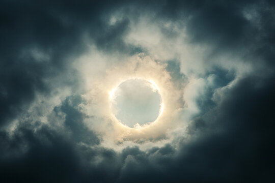 A sun halo glowing through heavy storm clouds - Powered by Adobe