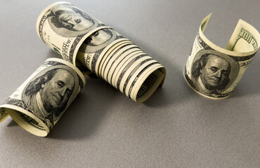 A close-up of a rolled up stack of one-dollar bills. Background with US dollars.