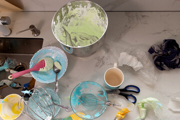 A pastry chef works in a lively kitchen creating colorful meringue and whipped cream. The counter is filled with mixing bowls, utensils, and vibrant frosting, showcasing a creative day of baking.