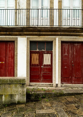 Exterior view of a building with three red doors and a balcony.