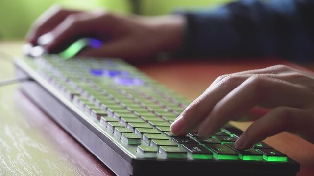 Young gamer plays a video game uses gaming illuminated keyboard 02