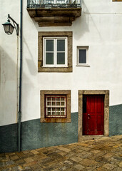 Exterior view of a building with a red door, windows, and a balcony.
