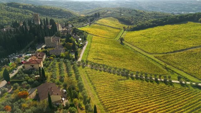 Abbazia di San Michele Arcangelo aerial 4k drone orbit flight with golden vineyards. Hidden gem in Italy Tuscany Chianti wine region. Medieval monastery and scenic landscape scenery