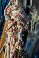 White and red braid-on-braid outhaul lines tied securely, their strength and precision reflecting safety and control at sea