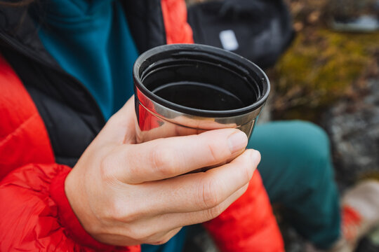 Detailed shot of hands gripping hot drink outdoors, Intimate portrayal of warm hands holding steaming cup outside, Close view of fingers grasping insulated mug in cold mountain air - Powered by Adobe