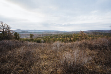 Fototapeta premium Broad scenic journey, Extensive outdoor landscape discovery, Vast valley with rolling hills beneath cloudy sky, Expansive countryside expedition with mountain ranges and overcast weather