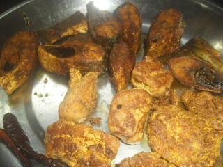 Fried fish pieces served on a plate with red chili peppers for a meal