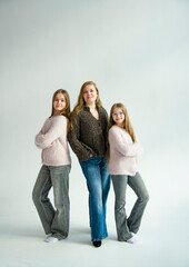 portrait of beautiful blonde smiling mother and daughter with long hair posing in white studio