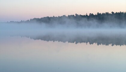 Soft mist over calm lake during sunrise showing peaceful natural reflection