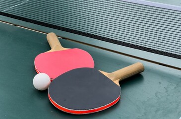 Two ping pong rackets and ball on table