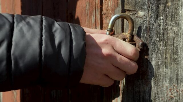 a man closes old doors with an old lock