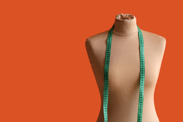 Mannequin for tailor with measuring tape on orange background