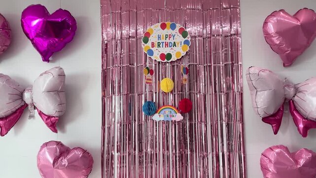 Colorful home birthday party decoration with balloons, ribbons, and happy birthday banner in cozy living room interior
