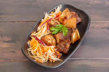 Griot de porc ha&iuml;tien servi avec pikliz aux poivrons, plat traditionnel cr&eacute;ole sur une table en bois. 