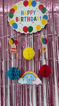 Colorful home birthday party decoration with balloons, ribbons, and happy birthday banner in cozy living room interior
