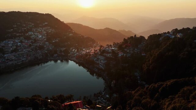 Aerial view of the tranquil Nainital Lake surrounded by lush forested hills and clusters of buildings, Nainital, Uttarakhand, India.