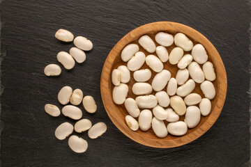 White uncooked beans on a stone, macro, top view.