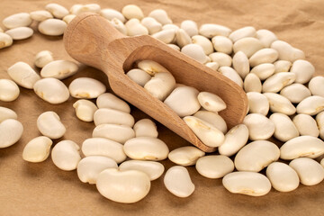 White uncooked beans on kraft paper, close-up.