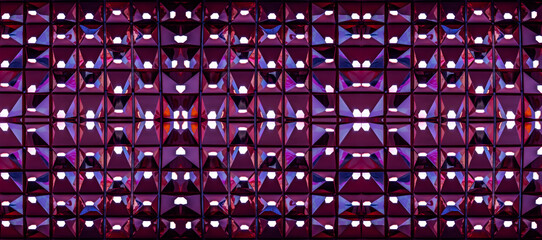 Fototapeta premium a reflective, geometric patterned wall with a grid of triangular and pentagonal shapes. Each shape reflects soft, pink and purple hues, creating a mesmerizing, abstract effect.