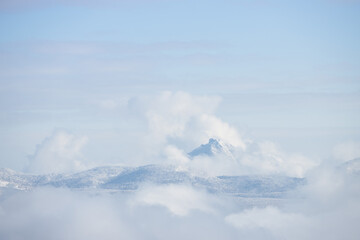 Fototapeta premium Snowy mountain peak surrounded by white fluffy clouds