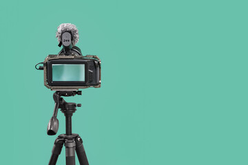 Professional camera on tripod against turquoise background