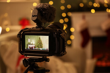 Professional camera on tripod against Christmas decorations in studio, closeup