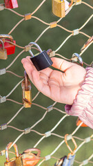 Close-up of child hand holding a padlock on the Makartsteg love lock bridge during family vacation in autumn Salzburg in Austria