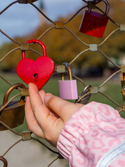 Child touching a red heart love lock on Makartsteg bridge during family vacation in Salzburg, Austria
