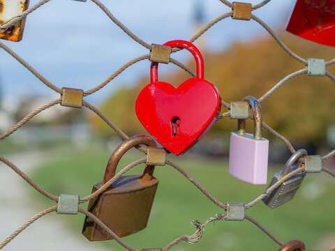 Bright red heart lock on Makartsteg bridge with Salzburg skyline in the background as promo for romantic European trip