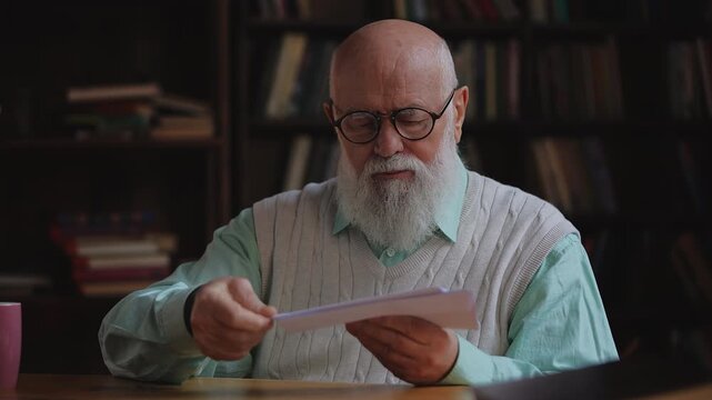 Male pensioner sorting postal mail at home, organizing letters and utility bills