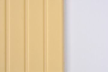 A white chocolate bar with vertical segments fills the left side of the frame, with the right side being empty white space