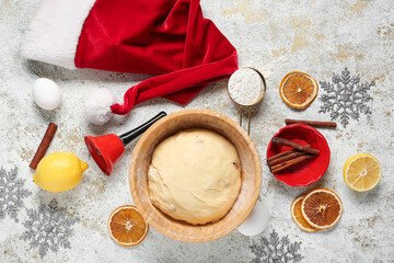 Bowl of dough for Panettone with ingredients and Christmas decor on light grunge background