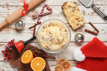 Bowl of dough for Panettone with ingredients and Christmas decor on white wooden background